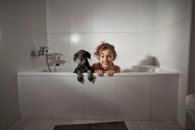 Content boy with dog in bathtub