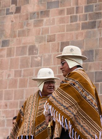 Peru - January, 02 2012: Peruvian men standing near stone wall