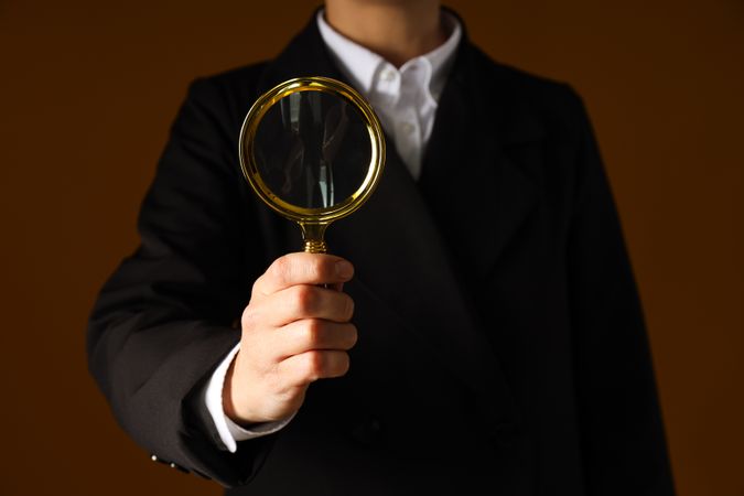 A businessman's hand holds a magnifying glass