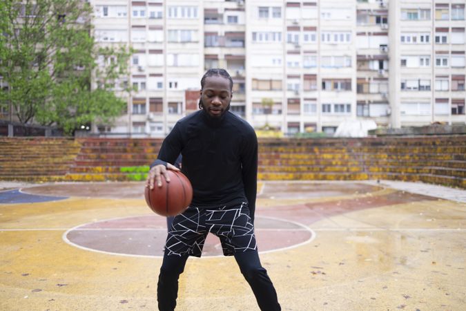 Young Black Man Dribbling Basketball Outdoors.
