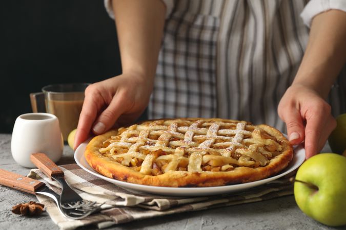 Housewife hold tasty apple pie on gray table. Homemade food