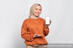 Muslim woman smiling while holding up smart phone mock up screen 0K1jY4