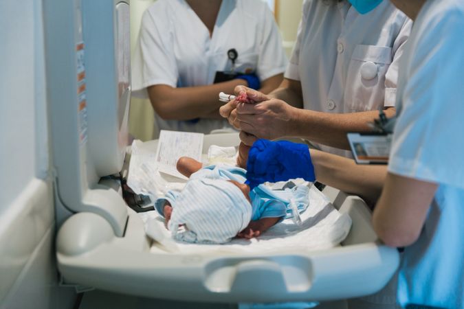 Team of professional doctors and nurses examining newborn baby at the hospital.