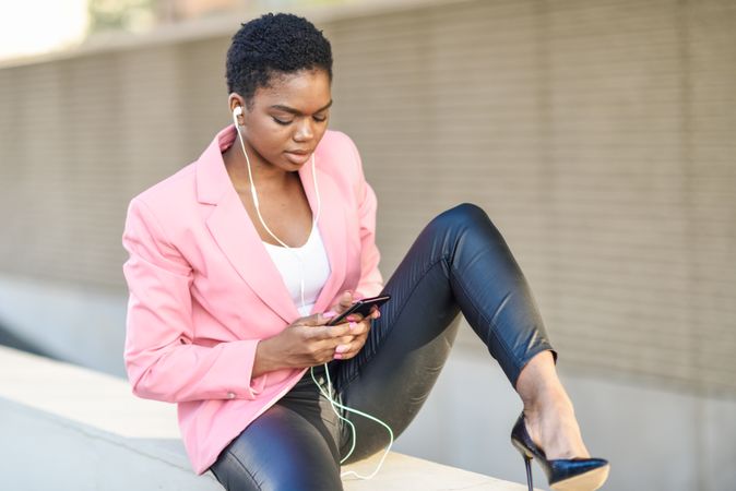 Female wearing suit with pink jacket texting on cell phone