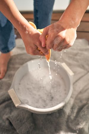 Crop person wringing out rag