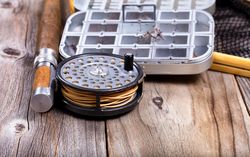 Vintage fly fishing reel and gear on rustic wood