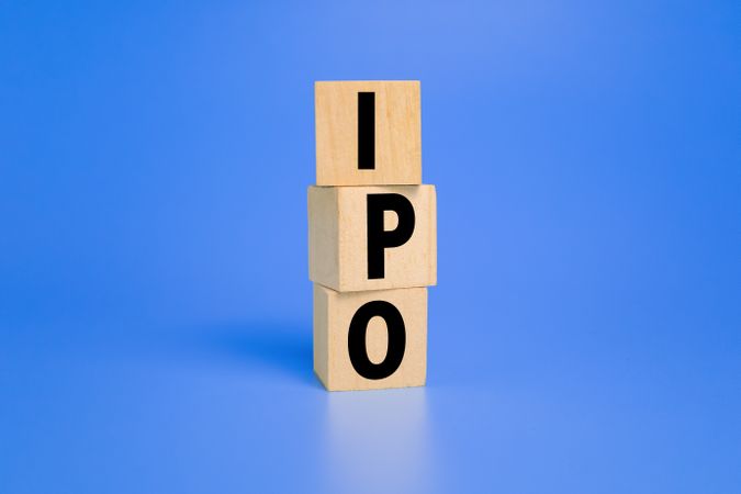 IPO letter text or initial public offering words on wooden blocks isolated on blue background copy space