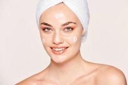 Delighted female with radiant skin applying cream