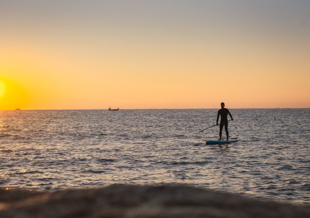 Man practicing paddle surfing with neoprene in a sunrise