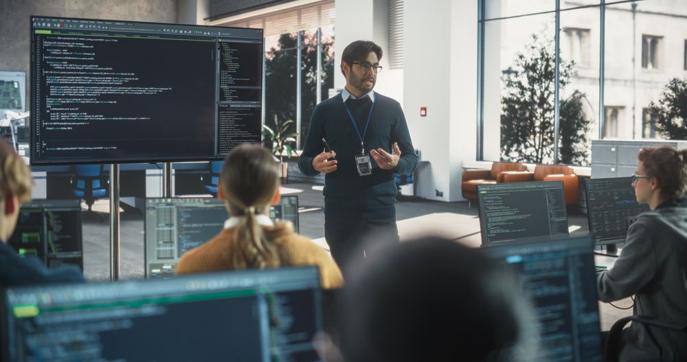 Teacher Giving Class to Diverse Multiethnic Group of Female and Male Students in College Room, Learning New Academic Skills on a Computer.