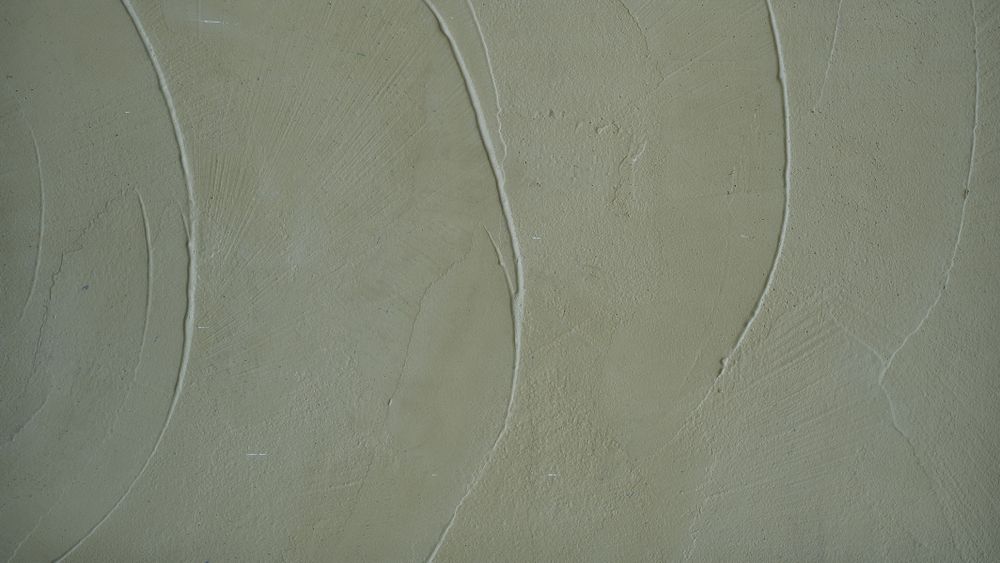 Smooth pale green concrete wall with plaster texture and curved surface pattern