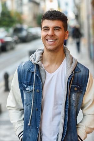 Smiling man in jean jacket walking on street