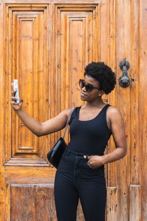 Young Black woman taking selfie on smartphone