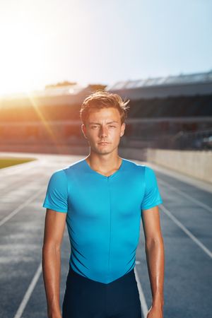 Young man after run standing on outdoor stadium race track