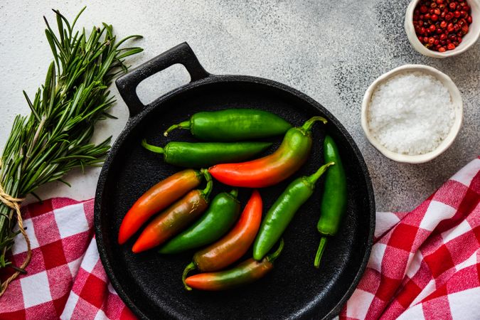 Iron cast pan with rosemary bunch and spicy peppers with seasoning