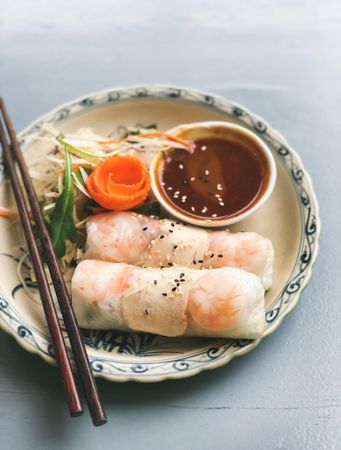 Spring rolls with dipping sauce, on blue table with copy space