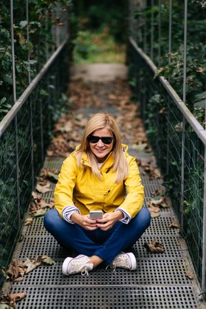 Happy female traveler taking selfie on suspension bridge in summer