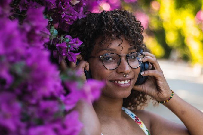 Black woman listening to music near flowers