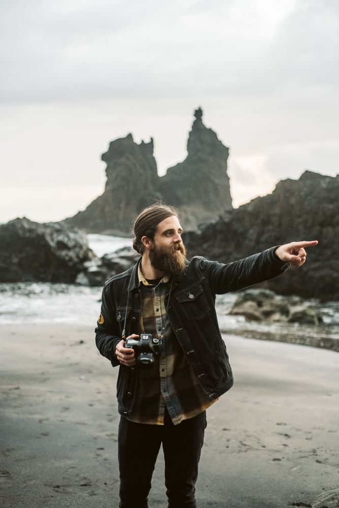 Bearded photographer standing near sea