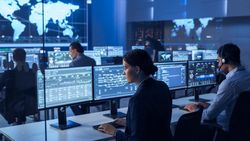 Diverse Professionals in a High-tech Control Room Monitor Global Data on Multiple Screens, Ensuring Cybersecurity and Efficient Operations.