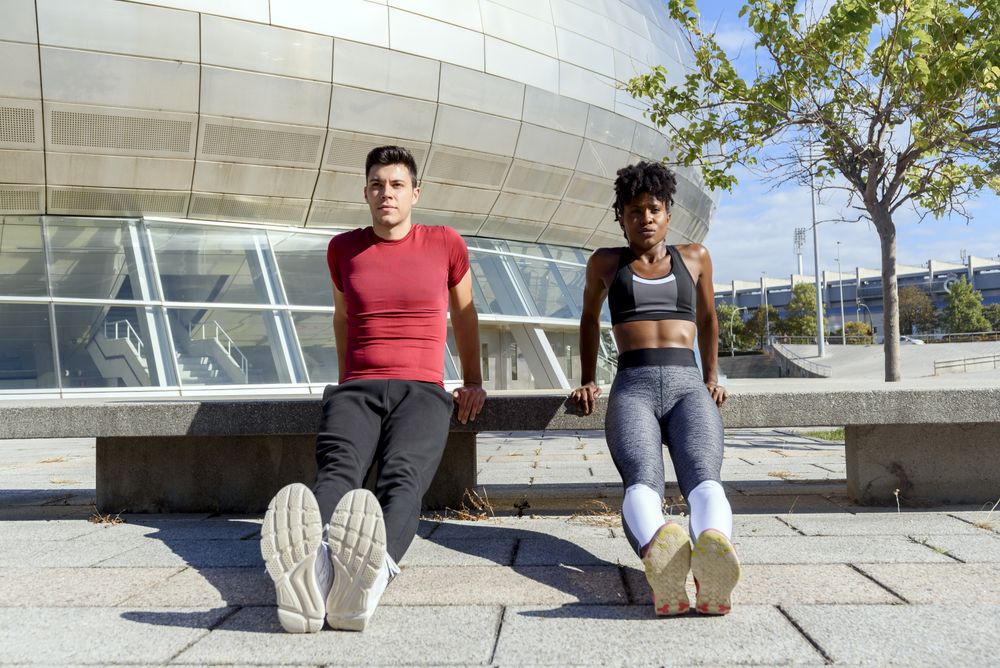 Young sportive people doing push up exercises in city