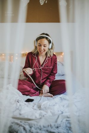 Woman with headphones listening to music in bed
