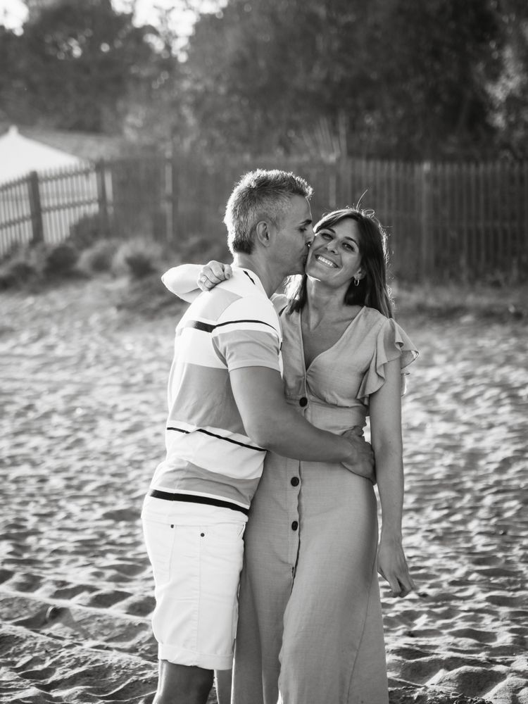 Laughing couple hugging on sandy beach