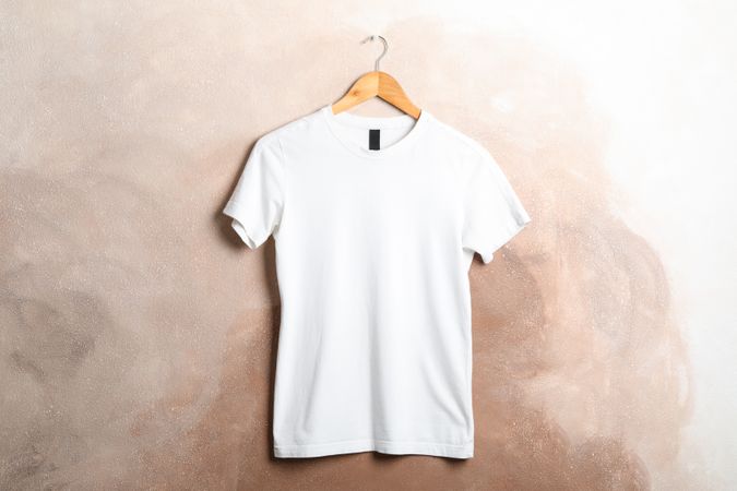Hanger with blank plain t-shirt on brown background, space for text