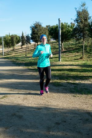 Woman in blue jogging outdoors on sunny fall day