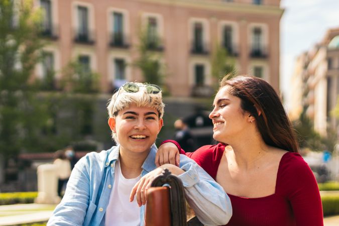 two women laughing and smiling sitting on a bench