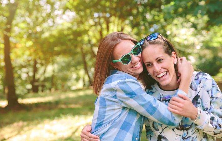 Happy women embracing and having fun over nature background