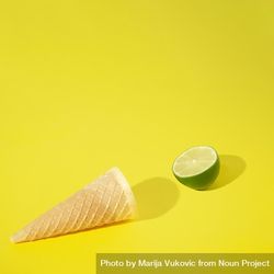 Ice cream cone with lime half on yellow background 56Vjd5