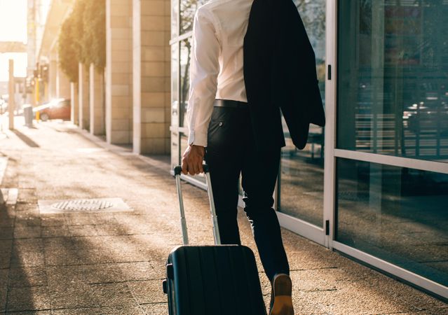 Business traveler pulling suitcase on city street