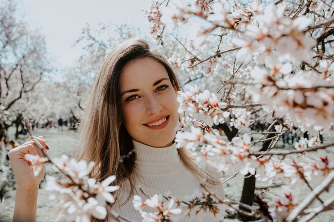 Young happy woman between trees in garden