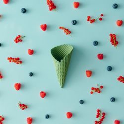 Green waffle cone on blue background with berries