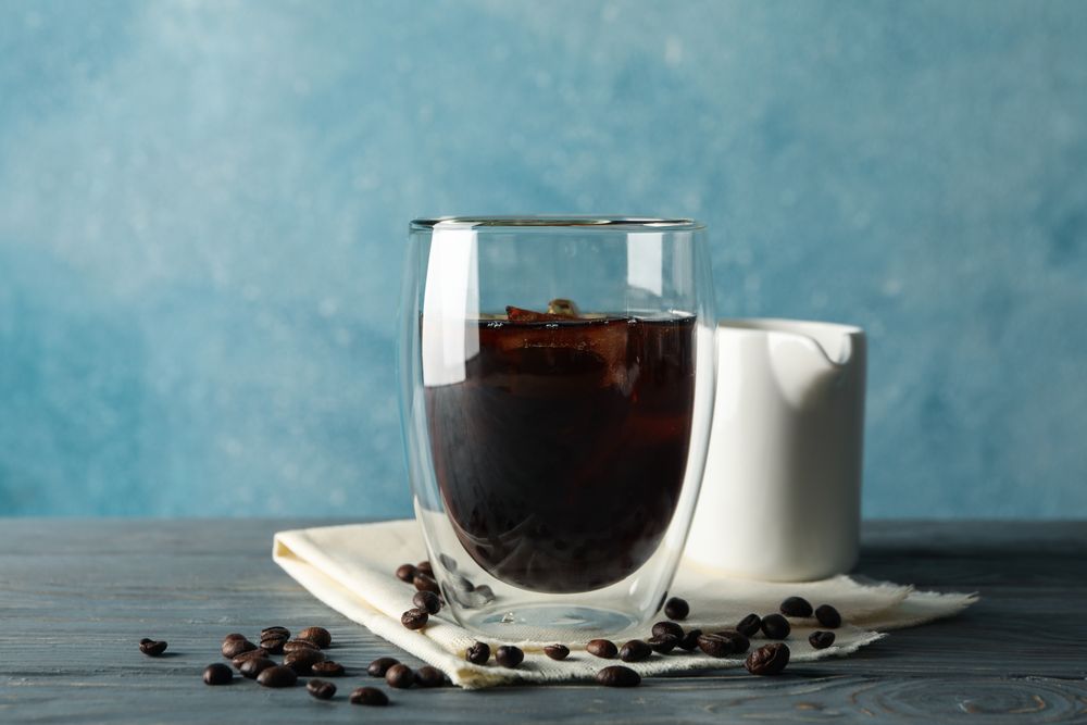 Composition with glass of ice coffee on wooden background