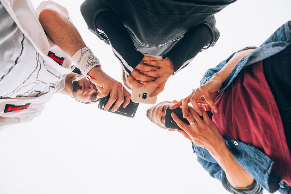 Stylish friends using smartphone outdoors