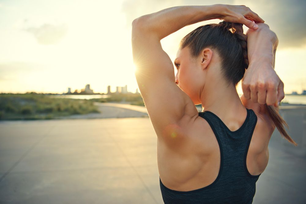 Muscular woman stretching her triceps