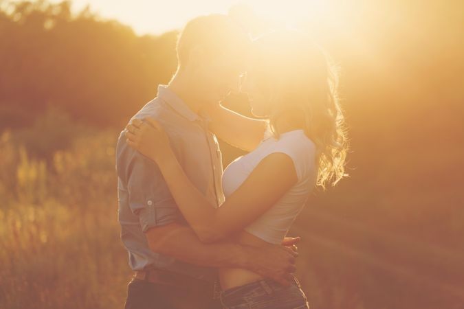 Backlit shot of couple embracing at sunset outside in summertime