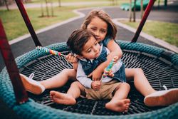 Two children on a swing in a playground