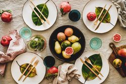 Fresh table setting with leaves on bright plates, pitcher, with fruit bowl