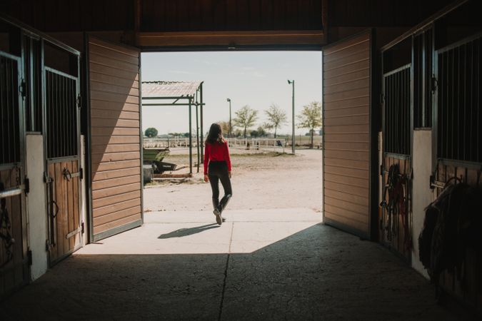 Woman in gates of horse stable