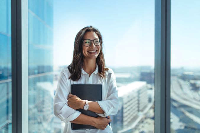 Happy business investor standing in office in a high-rise building overlooking the cityscape
