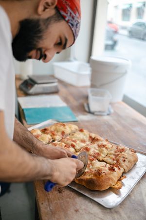 Arabic pizza maker cutting dough with cutter