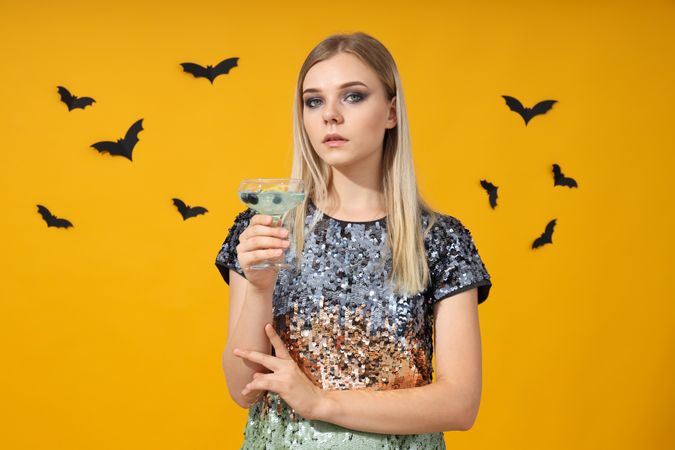 A woman at a party in the style of Halloween with a cocktail in her hands