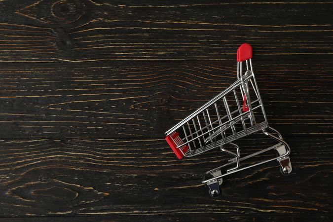 Shop cart on wooden background, space for text