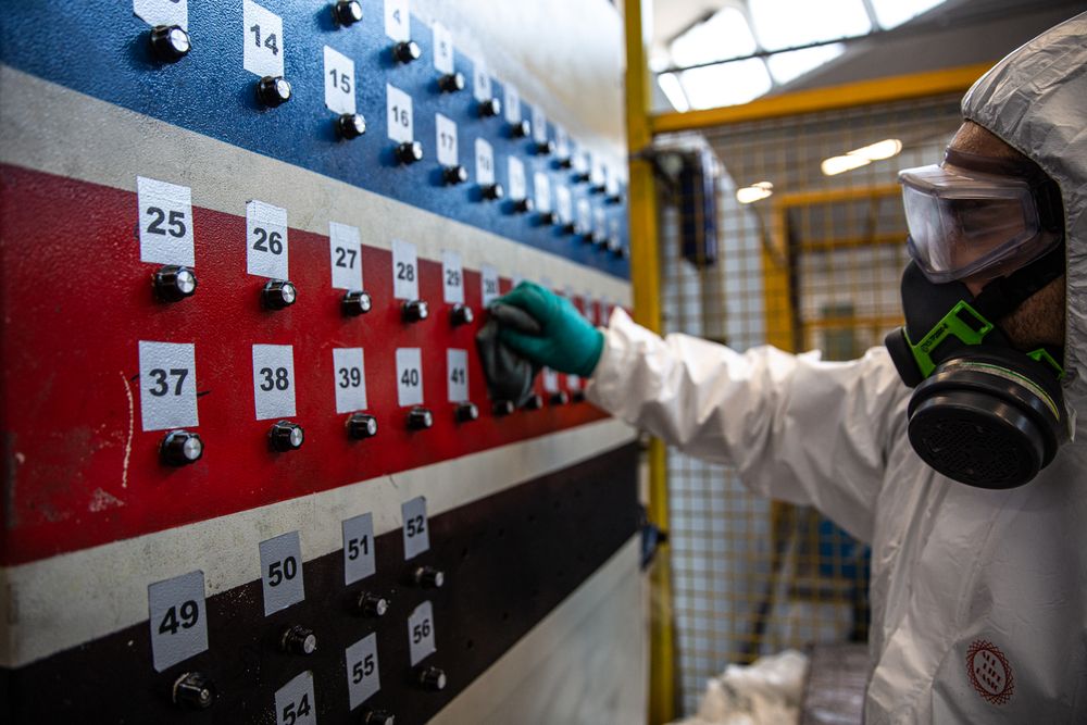 Person in PPE sanitizing a electric keys on wall during lockdown in Milano, Italy 
