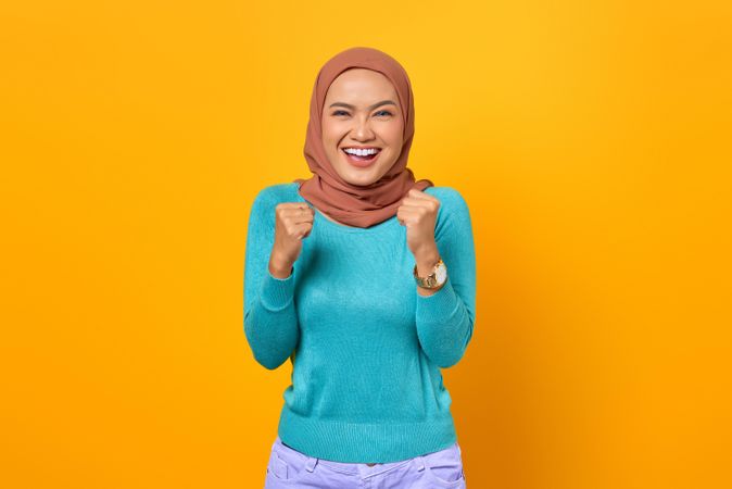 Excited Muslim woman with her clenching her fists in celebration
