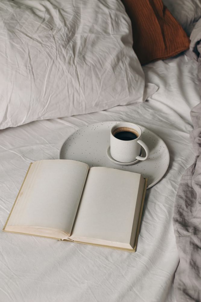 Cup of coffee, espresso with open book, diary mockup on bed sheet