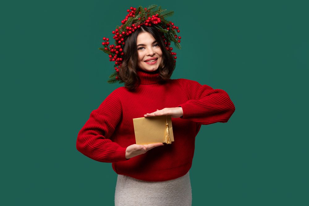 Woman in red sweater presenting golden envelope with both hands